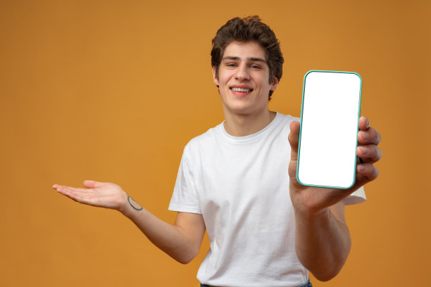 微笑的年轻人展示手机空白白屏幕的模型到相机。图片下载