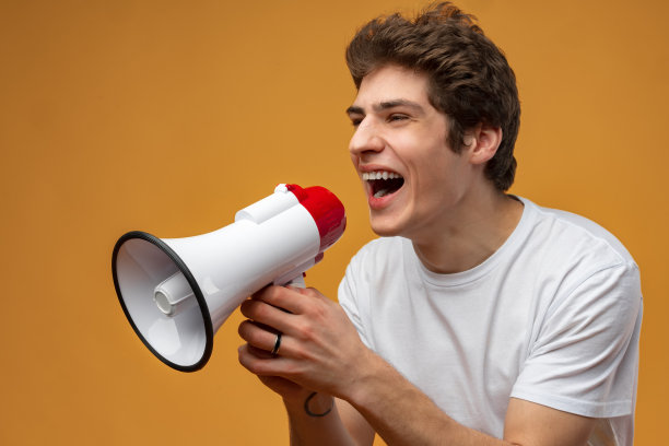 年轻人在黄色背景下对着扩音器喊话图片下载