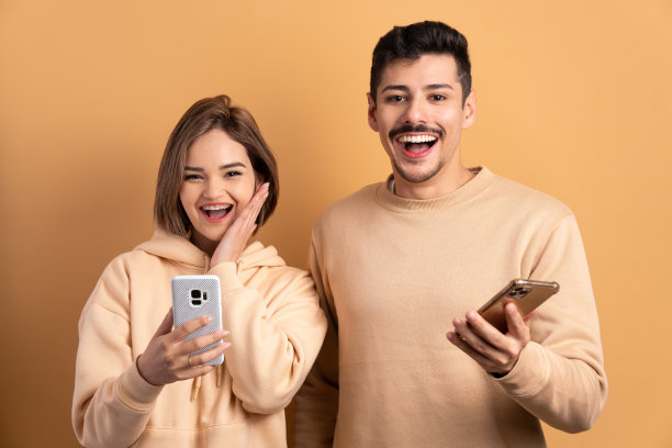 有趣的情侣在所有米色的智能手机上观看视频和照片。应用，社交媒体，成瘾，网络概念。图片下载