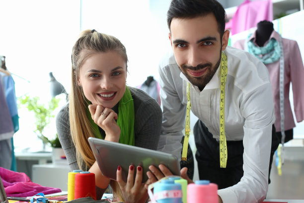 微笑的设计师造型师与客户讨论新衣服的剪裁，并拿着剪贴板图片下载