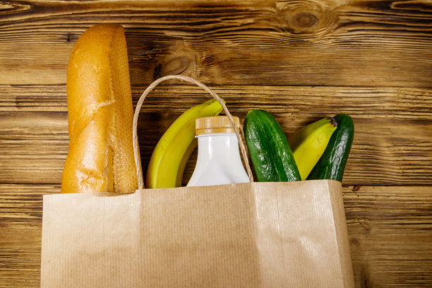用纸袋装着不同的食物放在木桌上。前视图。杂货购物概念图片下载