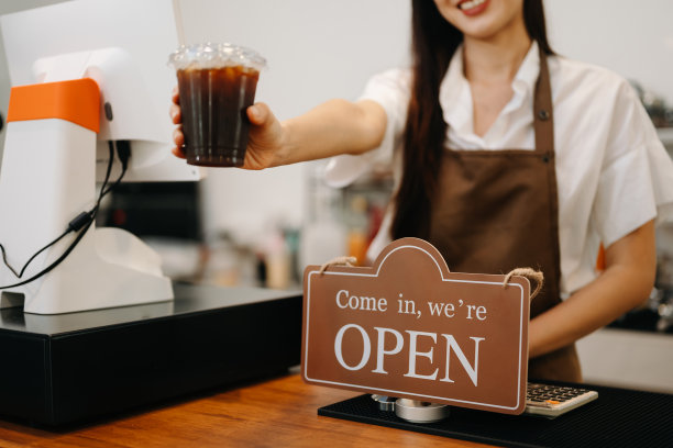 咖啡商业概念对着镜头微笑的美丽女士在咖啡馆提供一次性带走热咖啡图片下载