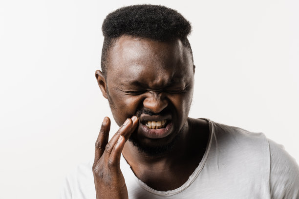 白色背景下非洲人牙痛。非洲裔美国人在白色背景下触摸脸颊，感觉牙齿受伤。蛀牙，牙齿或牙龈感染或受伤。图片下载