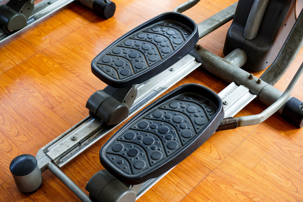 这张特写照片显示的是一个人在健身房的椭圆机上排队跑步。图片下载