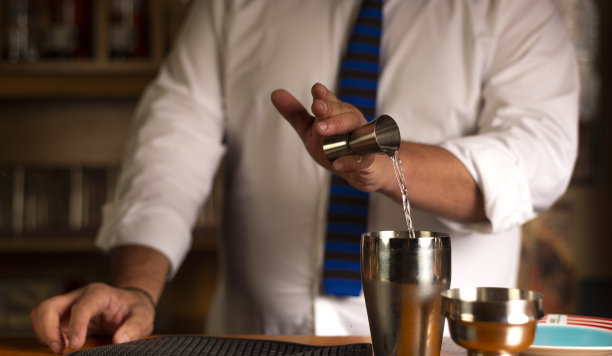 夜总会里一个调酒师的手特写，他把酒精倒进鸡尾酒摇酒器里准备鸡尾酒图片下载
