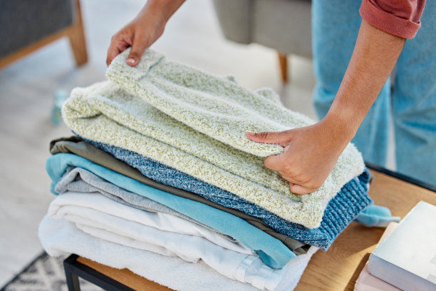 洗衣、做家务和女人拿着衣服的手，在一所房子的客厅桌子上折叠和分类。家务杂务，服务和家庭清洁与衣物从上面洗图片下载