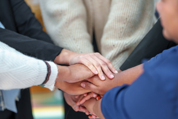 一群朋友伸出双臂，触摸双手，以示团结。图片下载