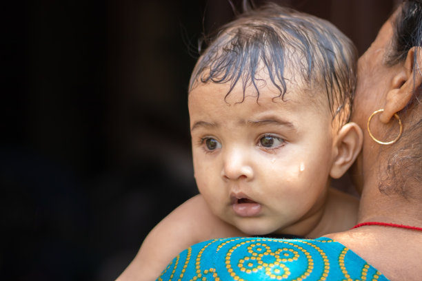 婴儿洗澡后平躺在祖母肩膀上的面部表情图片下载