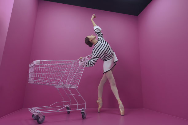 年轻的芭蕾舞女演员在白色紧身裤和半裙摆姿势从商店购物车图片下载