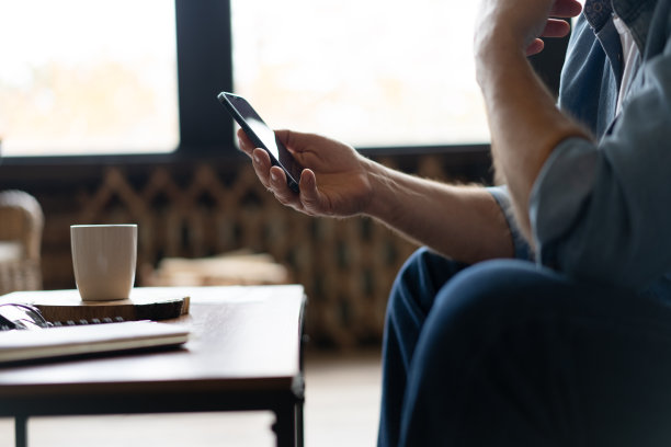 快乐的微笑老人使用智能手机设备，坐在家里的沙发上图片下载