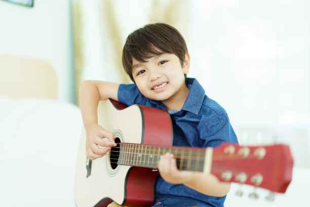亚洲小男孩练习弹吉他。图片下载