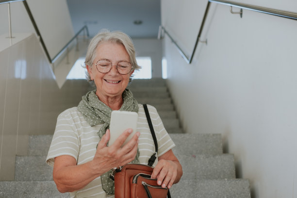 老年有吸引力的白人妇女的肖像坐在楼梯内的建筑物使用手机图片下载