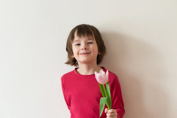 快乐的微笑女孩在红色t恤与粉红色的郁金香在白色的背景图片下载