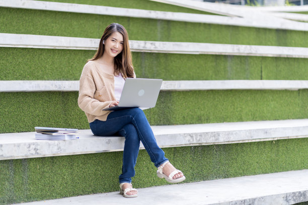 亚洲女学生在大学附近学习备考。通过连接到互联网的手机或笔记本电脑进行交流。知识来源丰富图片下载