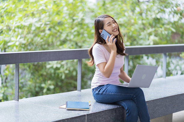 亚洲女学生在大学附近学习备考。通过连接到互联网的手机或笔记本电脑进行交流。知识来源丰富图片下载