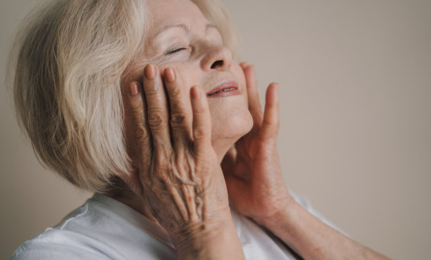 有吸引力的开朗的灰色头发的女人触摸丝滑的脸皮肤后剥离孤立的灰色粉彩背景图片下载