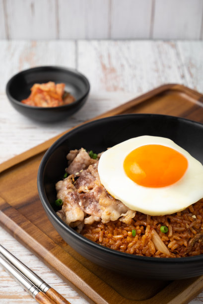 特写的泡菜饭与烤牛腩切片和煎蛋在黑碗在木桌上。图片下载