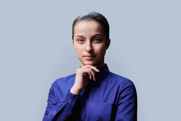 十几岁的女孩15、16岁的肖像，微笑着看着相机在灰色的背景图片下载