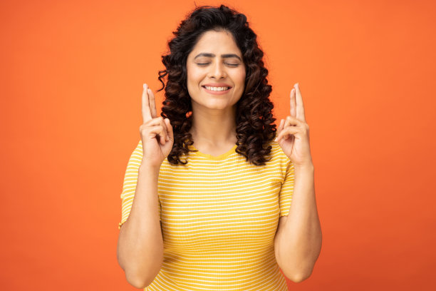 学生女孩交叉手指肖像询问考试成绩在橙色背景的股票照片图片下载