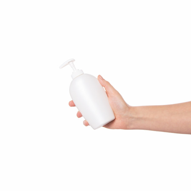 这只手拿着一个化妆品包装，白色背景上有一个可以吃的塑料瓶。皮肤和身体护理。白色瓶装身体乳，液体肥皂，洗发水。图片下载