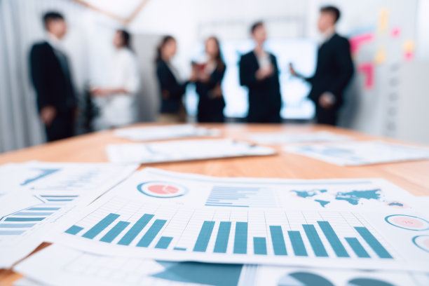 特写聚焦财经纸，模糊商界人士和谐互动。图片下载