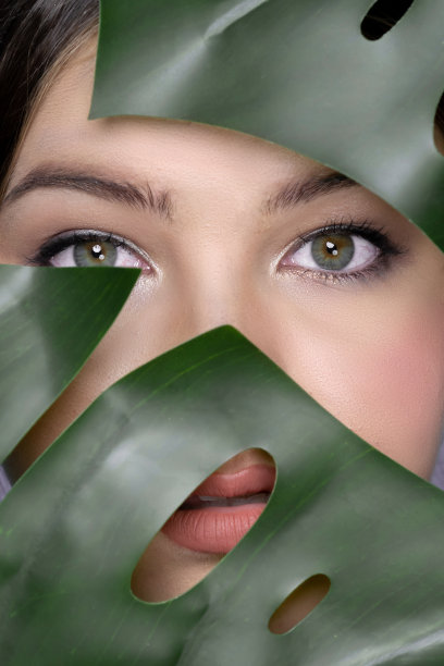 在美的概念中，迷人的女孩被绿叶覆盖的特写肖像脸图片下载