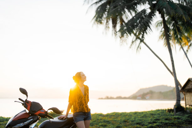 女人站在摩托车附近，背景是大海图片下载