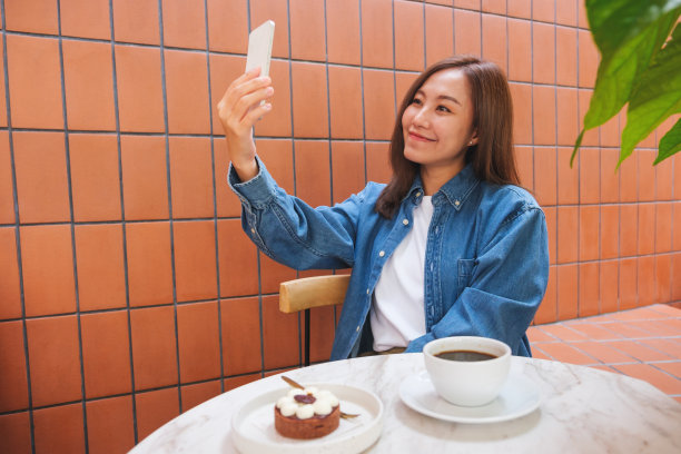 一名年轻女子在咖啡馆用手机自拍的肖像图像图片下载