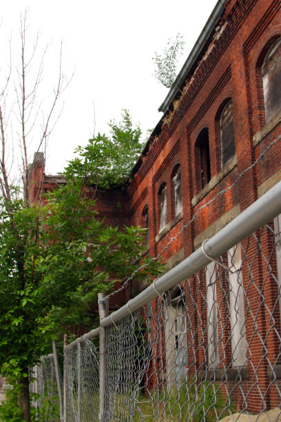 旋风围栏前的一个旧废弃和木板红砖工厂。图片下载