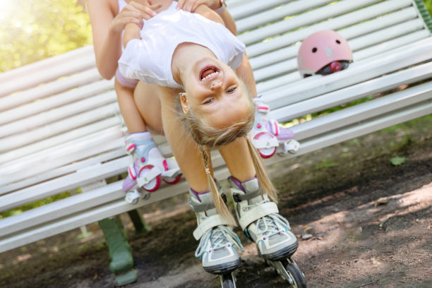 母女俩一起在公园滑完直排轮滑后在长椅上玩耍。周末家庭休闲体育活动。复制负空格图片下载