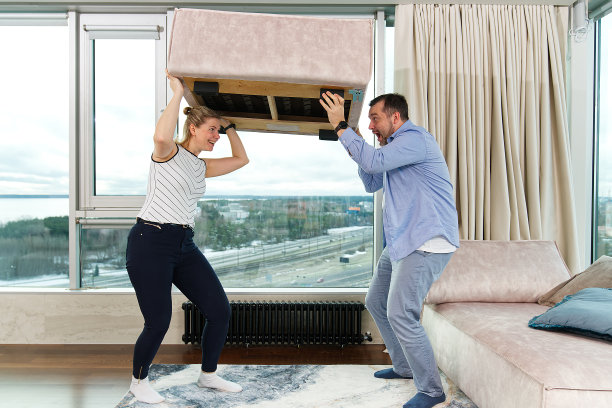 一家人搬运家具：幸福的夫妇在新公寓里搬运家具图片下载