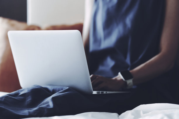 一个女人在卧室里操作笔记本电脑图片下载