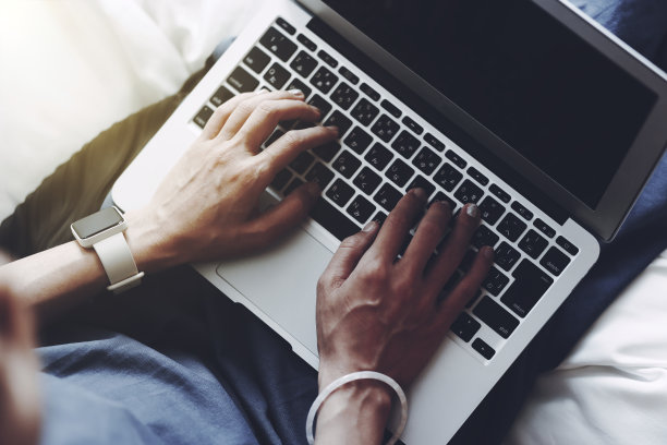 一个女人在卧室里操作笔记本电脑图片下载