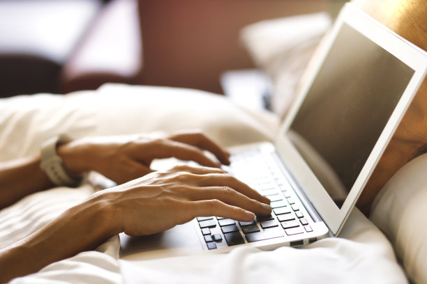 一个女人在卧室里操作笔记本电脑图片下载