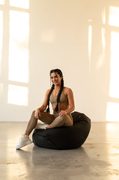 运动迷人的女孩在健身服摆姿势坐在一个pouf。训练后休息。黑白照片图片下载