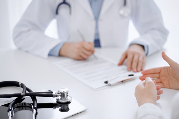 听诊器放在平板电脑上，医生和病人面对面坐在后面。医学、保健概念图片下载