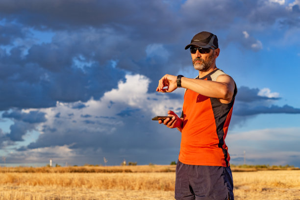 男运动员收腰的照片，在他的智能手机上测量脉搏和检查训练数据。农村环境图片下载