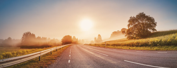 雾蒙蒙的早晨，日出在空旷的柏油路上。图片下载