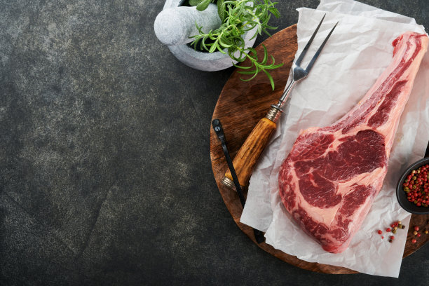新鲜的生牛排。干燥陈年生战斧牛排加香草和盐在旧木头背景上。准备烧烤。俯视图和复制空间。图片下载