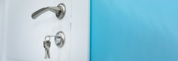 把钥匙插进白色门上的钥匙孔。图片下载