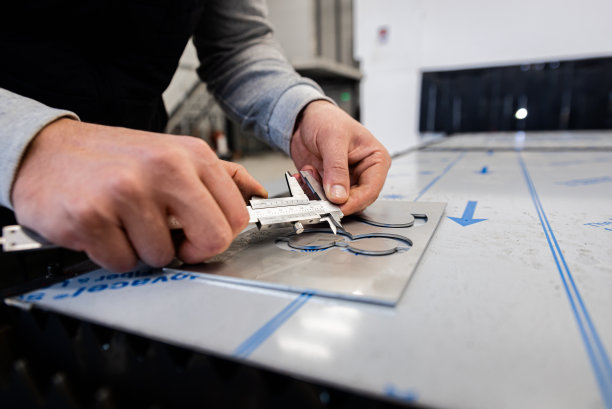 用游标卡尺检查激光切割金属板的人手特写。图片下载