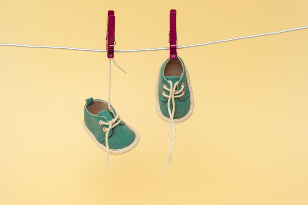 婴儿鞋挂在晾衣绳上。新生的概念图片下载