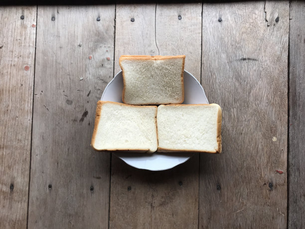 面包在木质背景上。乡村黑麦。新鲜的面包的乡村传统的木质纹理背景。面包店有硬皮面包。烘焙产品标签、设计等设计元素图片下载