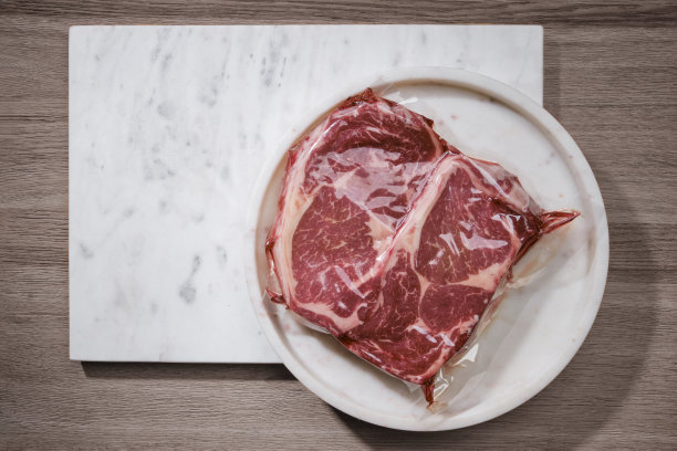 真空包装肉类。白色大理石背景上的生牛排图片下载