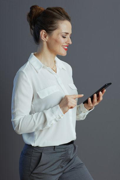 微笑的女员工用手机发短信孤立在灰色图片下载