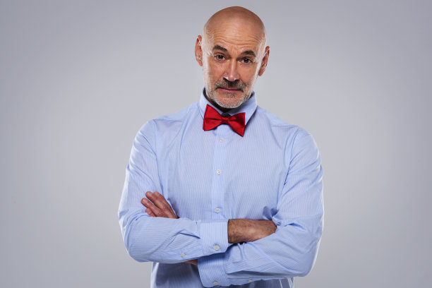 一个自信的商人戴领结站在孤立的背景的工作室肖像图片下载