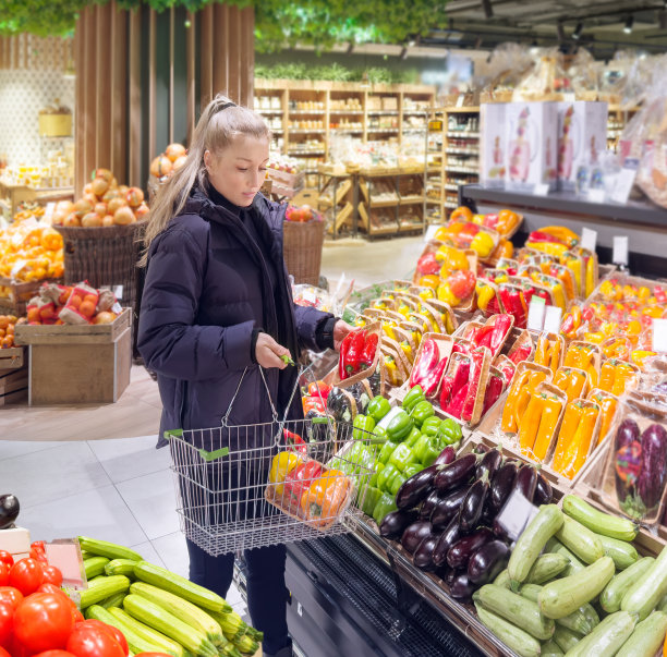 一名妇女在市场上购买蔬菜(辣椒、辣椒、茄子、西葫芦)图片下载