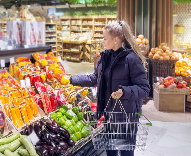 一名妇女在市场上购买蔬菜(辣椒、辣椒、茄子、西葫芦)图片下载