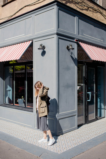 一个背着背包的女孩站在一个漂亮的咖啡馆大楼的角落里。旅行和城市散步的概念图片下载