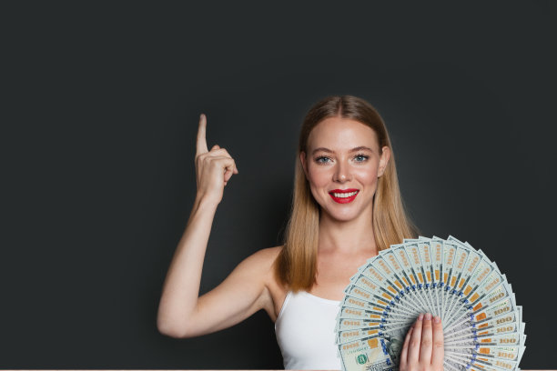 快乐的美女指着灰色背景上的钱扇图片下载